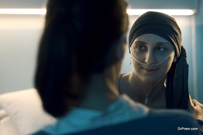 Friend supporting her friend with cancer at the hospital, they are smiling at each other