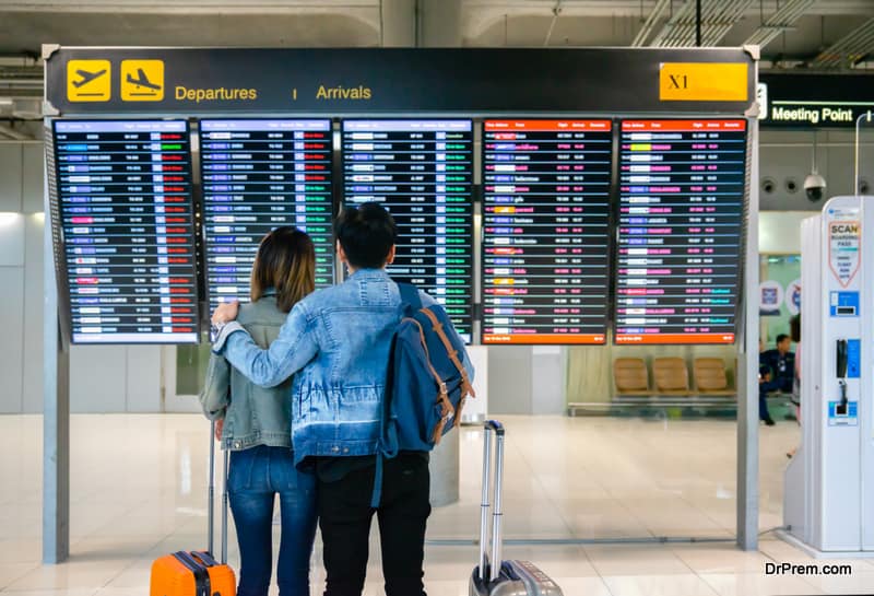 Asian couple check flight at the international airport to travel on weekends , tourism and holiday concept.