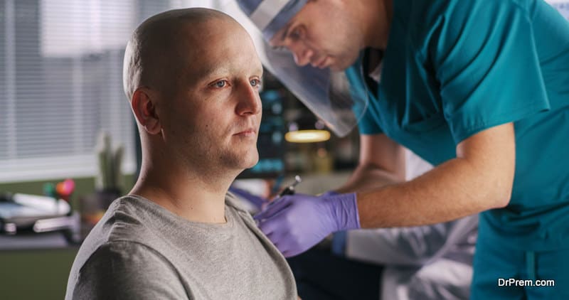 Bald male patient with cancer talking with mature doctor