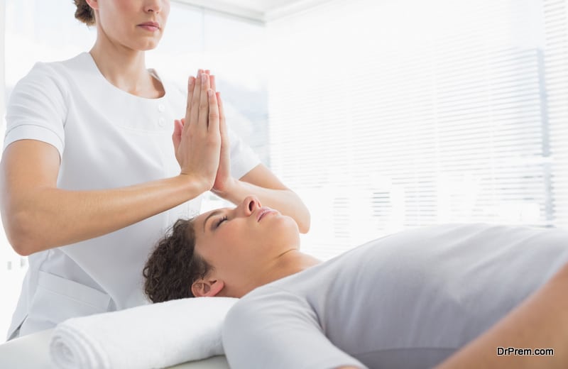 Female therapist giving Reiki treatment to woman at health spa
