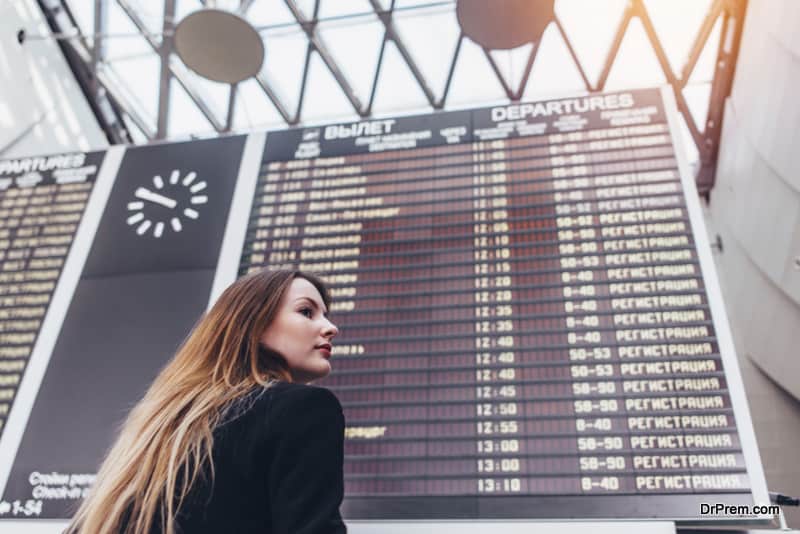 Young woman standing against flight timetable in airport