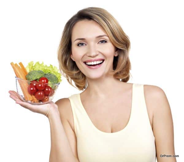 Portrait of a young smiling woman with a plate of vegetables.