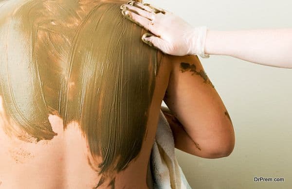 A sea mud full body wrap at a luxury spa being applied to the back and shoulders.