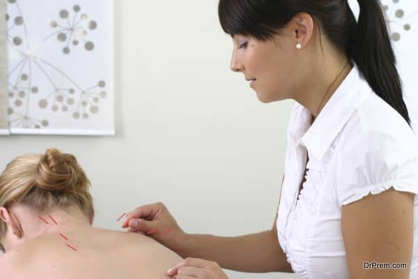 acupuncturist inserting needles into client's back