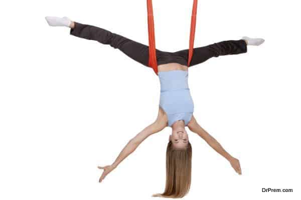 Young woman making antigravity yoga exercises with red hammock on a white background