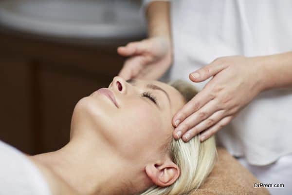 people, beauty, spa, healthy lifestyle and relaxation concept - close up of beautiful young woman lying with closed eyes and having face or head massage in spa