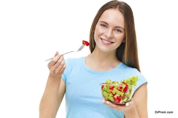 Portrait of a fit healthy woman eating a fresh salad isolated on white background.