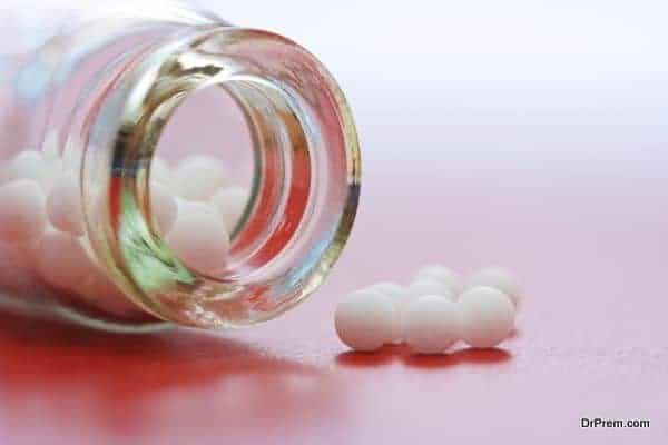 Close view of homeopathic medication - small white balls in glass bottle