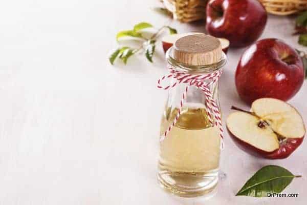 Apple cider vinegar and red apples over white wooden background with copyspace. Selective focus
