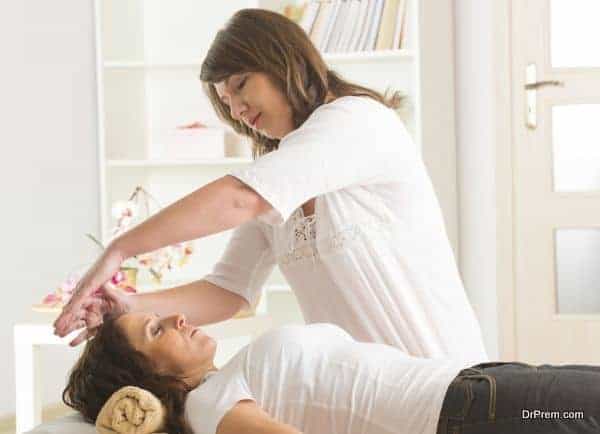 Professional Reiki healer doing reiki treatment to young woman