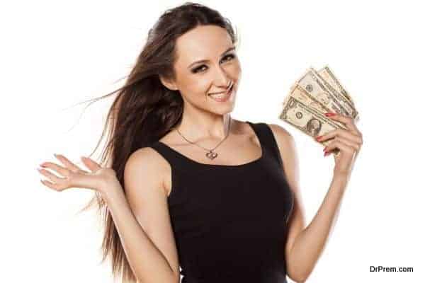 Young girl cooling herself with a fan of money