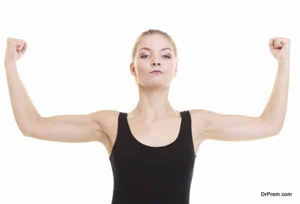 Fitness woman showing fresh energy flexing biceps muscles isolated on white background. Girl in sportwear energetic and fun.