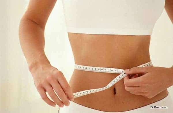 Woman measuring her waistline with tape measure