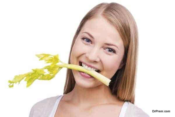 Celery fun. Beautiful young woman holding celery in her mouth an