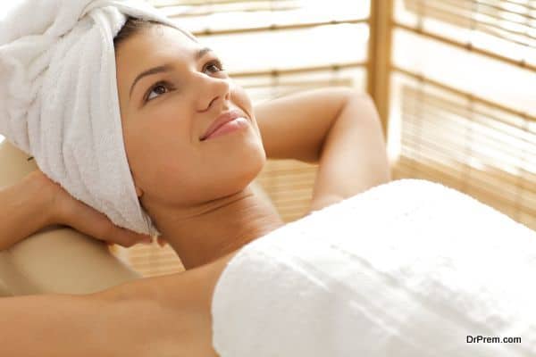 Close-up of young woman relaxing on massage table with hands beh