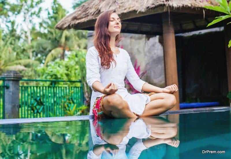 Woman meditating at pool side