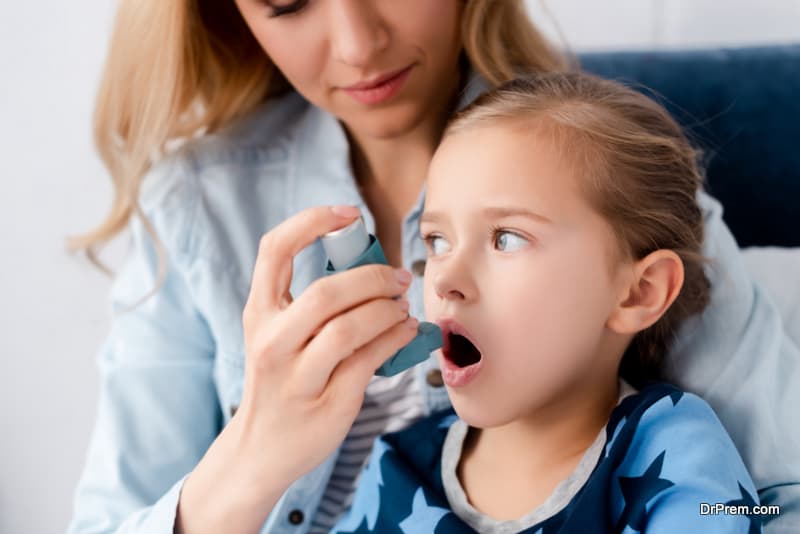 caring mother holding inhaler near asthmatic daughter