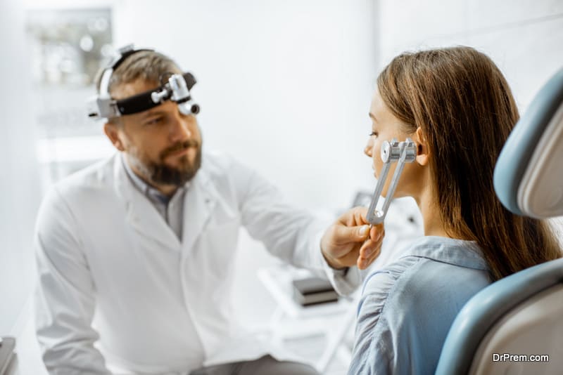 Senior otolaryngologist examining ears with ENT tuning fork for a young patient in the medical office. Hearing test with tuning fork concept