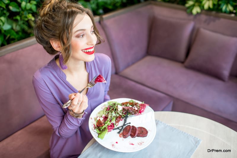 View from above on the beautiful woman in violet dress eating healthy salad 