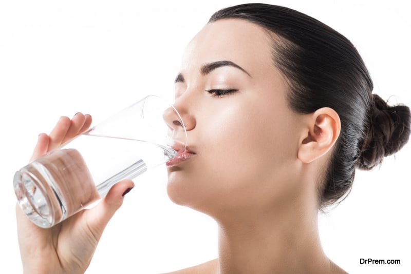 side view of beautiful girl drinking water from transparent glass isolated on white