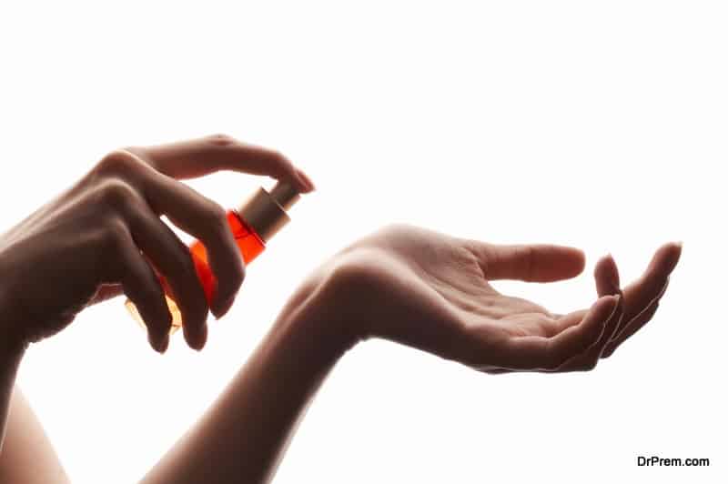 woman applying perfume on her wrist, bright red perfume bottle