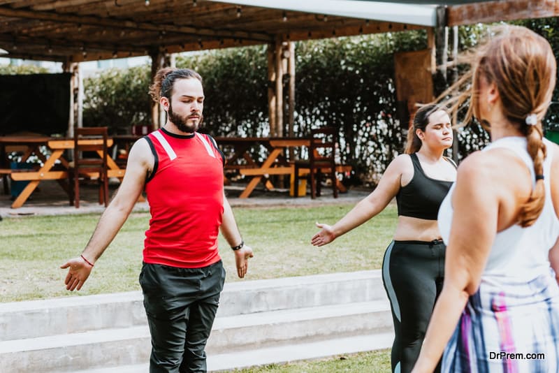 Young latin people in yoga class doing breathing exercises with instructor outdoors in Mexico City