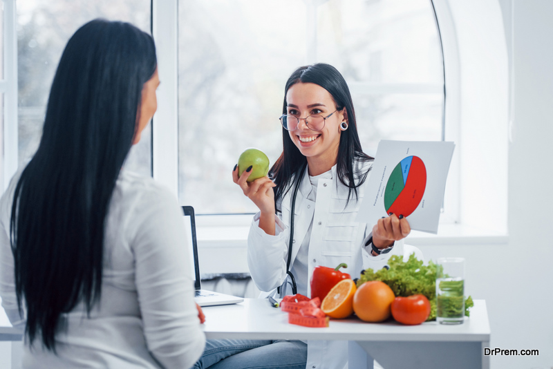 Female nutritionist with graph gives consultation to patient indoors in the office.