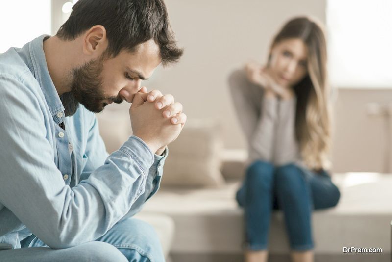 Young man feeling sad after arguing with his girlfriend on sofa at home.