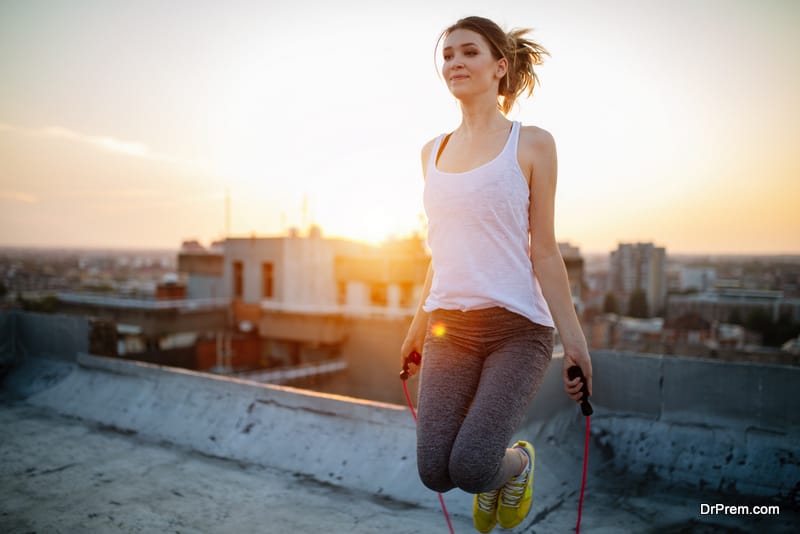 Portrait of fit young woman with jump rope. Fitness female doing skipping workout outdoors on a sunny day.