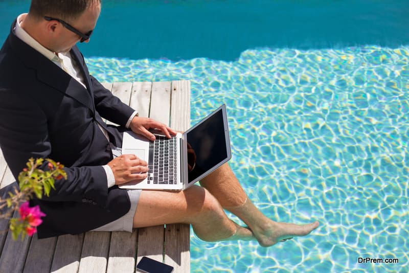 Businessman working with laptop computer by the pool.