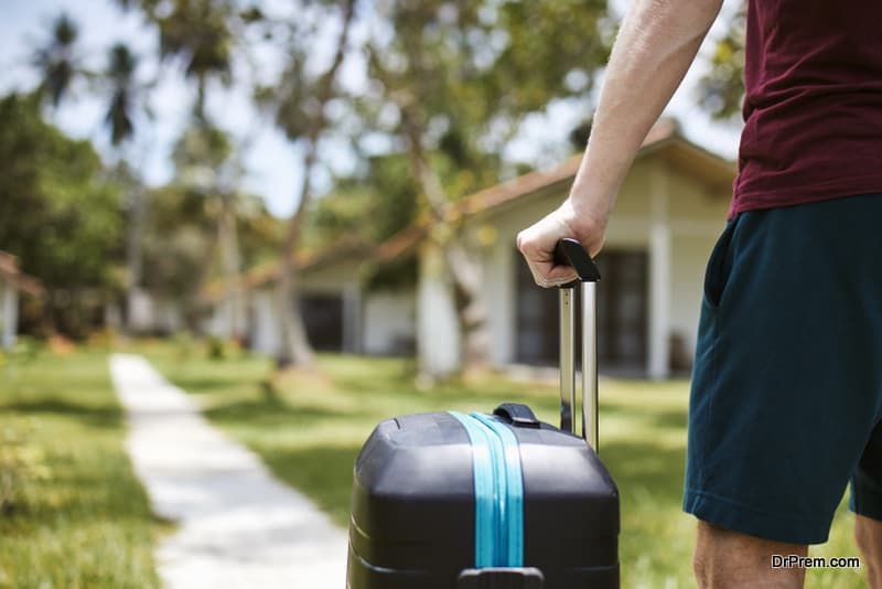 Man holding suitcase on footpath in luxury tourist resort