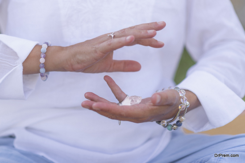 Female crystal healing therapist meditating, manifesting abundance with white selenite crystal. Energy work