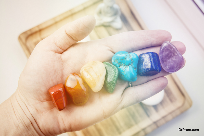 Woman hand sowing all seven color chakra crystal stones. Chakra energy flow healer concept.