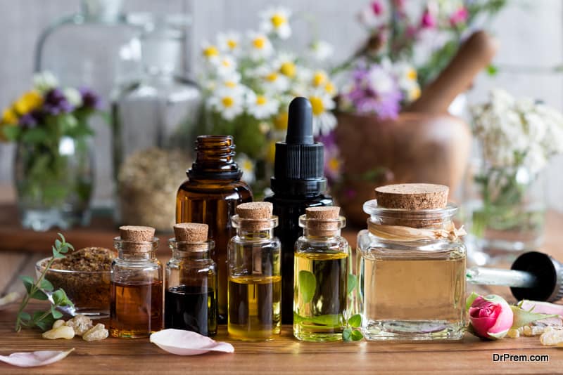 Selection of essential oils with various herbs and flowers in the background