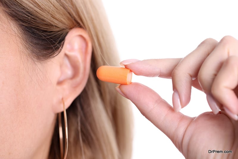 Woman inserts orange earplugs into ears