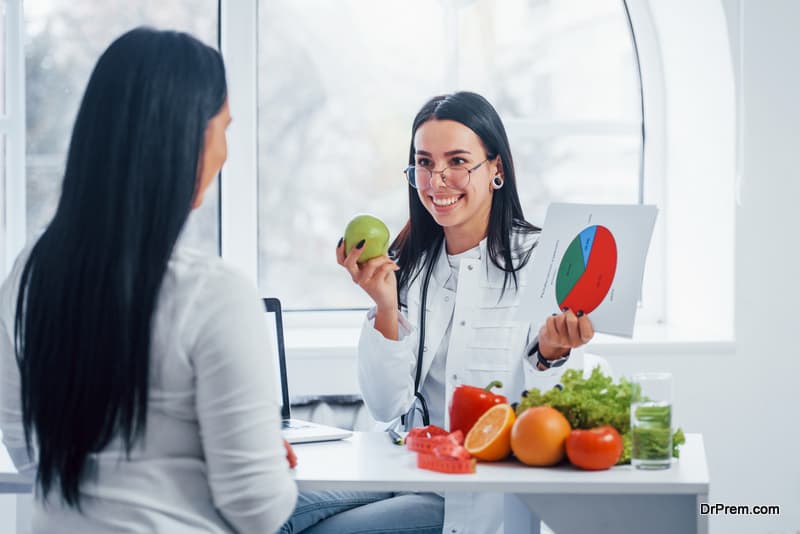  Female nutritionist with graph gives consultation to patient indoors in the office