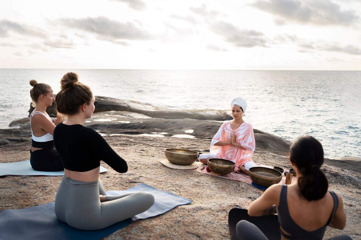 senior-meditation-guide-with-singing-bowls-sea_23-2149386445
