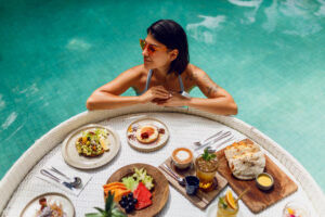 Is Italy the Next Global Longevity Hub? Dr Prem’s Insights into The Mediterranean’s Wellness Reawakening. 5 Is Italy the Next Global Longevity Hub? Dr Prem’s Insights into The Mediterranean’s Wellness Reawakening. young sexy woman with tattoo bathing suit having breakfast private pool girl relaxing pool drinking coffee eating fruits fruit plate smoothie bowl by hotel pool