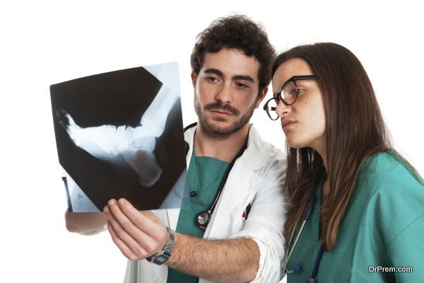 Young bearded orthopedic doctor and beautiful female surgeon control patient x-ray. Close up. Caucasian. Isolated on white.