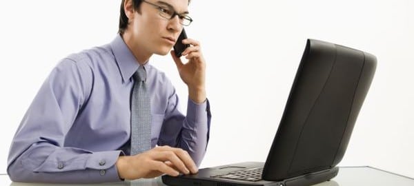 Businessman on laptop and cell phone.