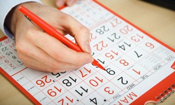 Office worker marking calendar with red pen