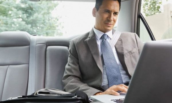 Businessman using laptop in backseat of car