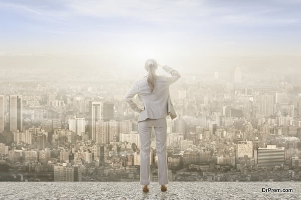 Concept of success with businesswoman standing on the roof and looking ahead for the opportunities. Rear view.