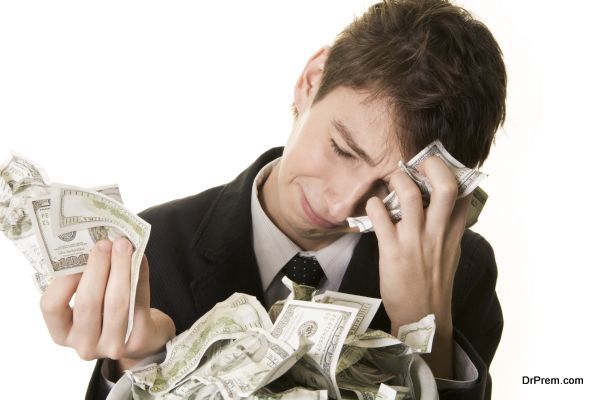 Conceptual image of grieving young businessman over heap of crumpled dollars