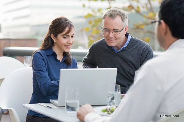 Man and woman look at a computer in cafe.