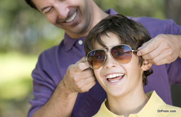 Father putting sunglasses on son