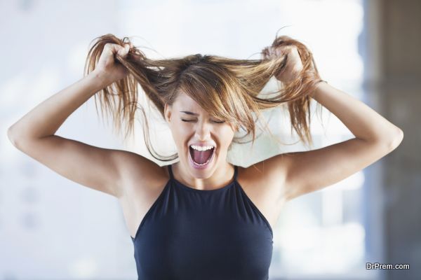 Frustrated young woman screaming and pulling her hair