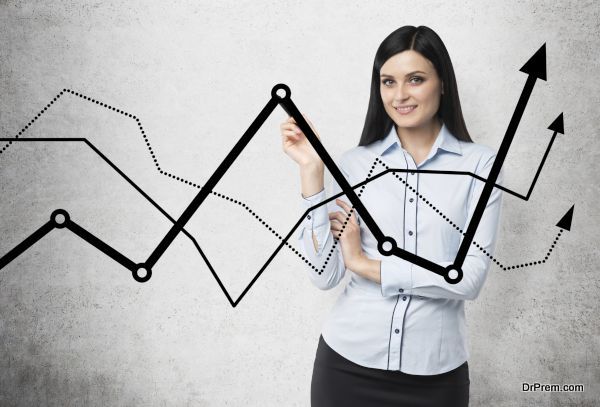 Brunette business lady presents a line graphs, which symbolise fluctuation of the business process. Concrete background.