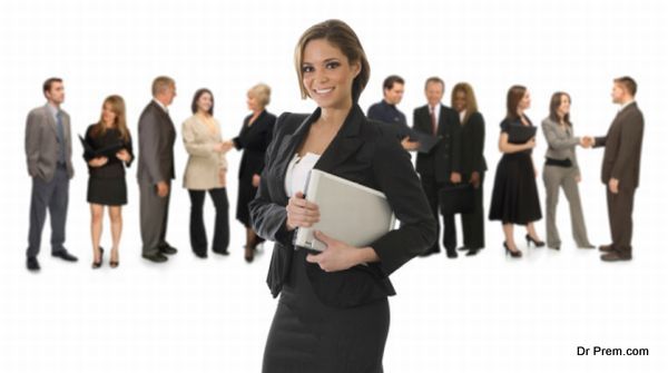 Young, pretty professional woman standing in front of a white background holding a laptop